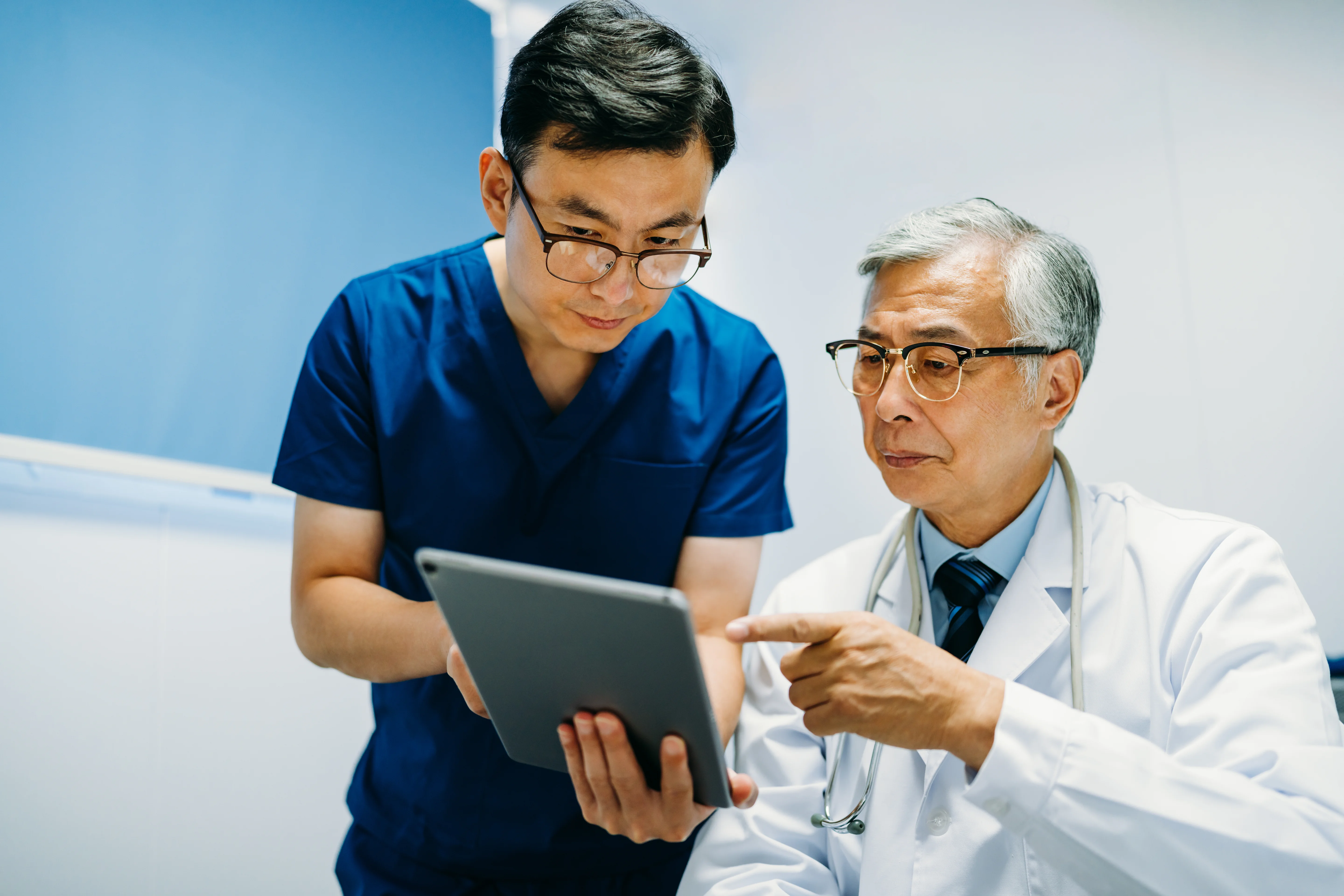 Two doctors using a digital tablet for an online consultation.